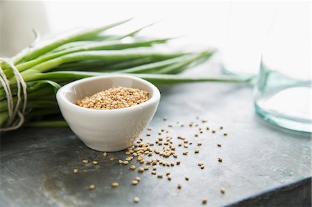 A Bowl of Sesame Seeds with Some Spilled; Green Onions in Background Foto de stock - Sin royalties Premium, Código: 659-07069134