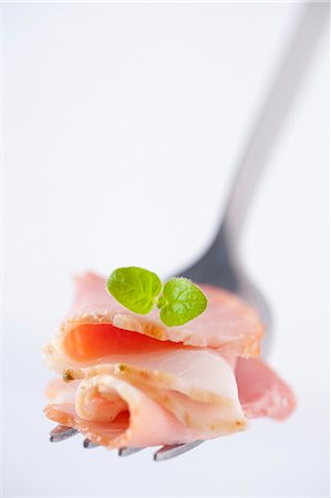 simsearch:659-02211875,k - Sliced ham with an oregano leaf on a fork (close-up) Photographie de stock - Premium Libres de Droits, Code: 659-07069161