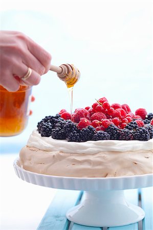 Honey being drizzled over a berry pavlova Foto de stock - Sin royalties Premium, Código: 659-07069183