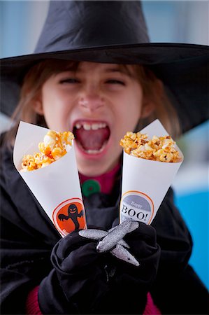 dining celebration - A girl holding paper cones of caramelised popcorn for Halloween Foto de stock - Sin royalties Premium, Código: 659-07069269