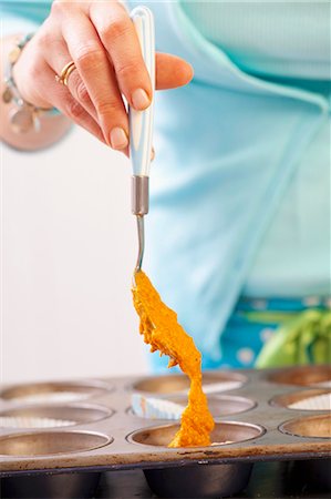 A woman spooning carrot cake batter into a baking tin Stock Photo - Premium Royalty-Free, Code: 659-07069272