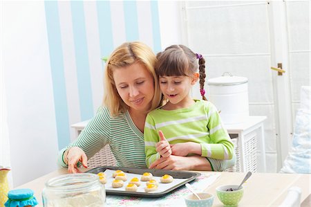 A mother and daughter with a baking tray with unbaked jam biscuits Stock Photo - Premium Royalty-Free, Code: 659-07069388