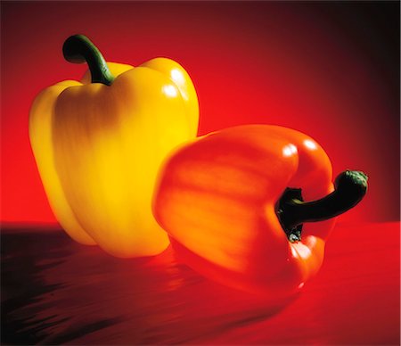 paprika - An orange and a yellow pepper on a red surface Stockbilder - Premium RF Lizenzfrei, Bildnummer: 659-07069676