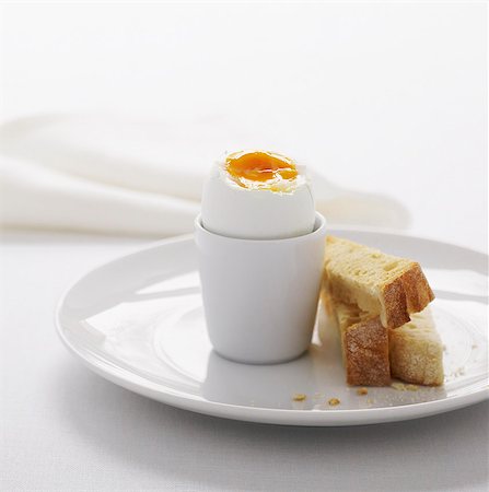 pochiert - A boiled egg in a white egg-cup with three fingers of lightly toasted bread Photographie de stock - Premium Libres de Droits, Code: 659-07597046