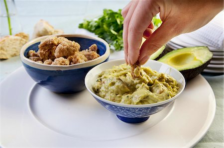 simsearch:659-07597105,k - Breaded chicken bites being dipped in guacamole Foto de stock - Royalty Free Premium, Número: 659-07597105