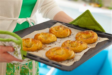 simsearch:659-06495090,k - Woman holding baking tray with freshly baked yeast pretzels Stock Photo - Premium Royalty-Free, Code: 659-07597238