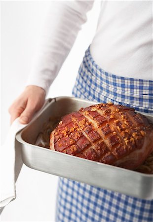 A woman holding a roasting tin with a roast crackling joint of pork Stock Photo - Premium Royalty-Free, Code: 659-07597278