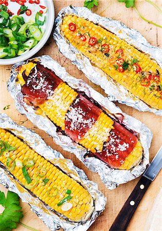 Corn cobs with Parma ham, parmesan, spring onions and sliced chillies, in aluminium foil Stock Photo - Premium Royalty-Free, Code: 659-07597653
