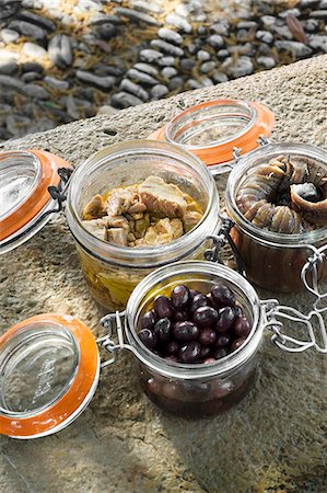 Preserved tuna, anchovies and olives in jars on a stone wall Photographie de stock - Premium Libres de Droits, Code: 659-07597899