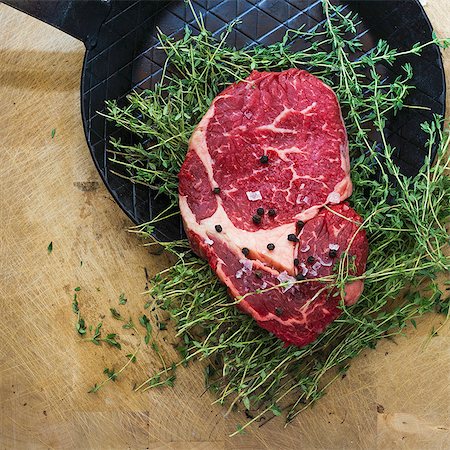 steak ingredients - Rib eye steak with thyme on a black frying pan Stock Photo - Premium Royalty-Free, Code: 659-07597989