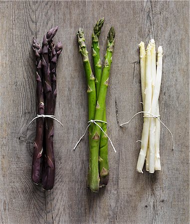 Purple, green and white asparagus stalks on a wooden surface Stock Photo - Premium Royalty-Free, Code: 659-07597980