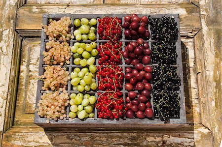 stachelbeere - Assorted berries in an old wooden crate on a wooden surface (currants, gooseberries) Photographie de stock - Premium Libres de Droits, Code: 659-07598144