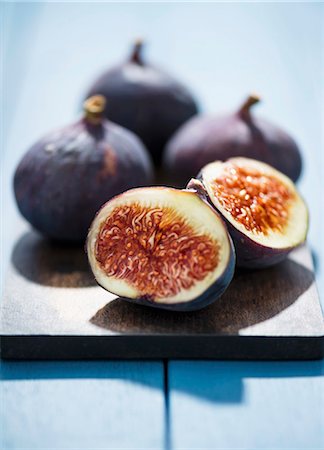 figue - Fresh red figs on a chopping board, one cut in half Photographie de stock - Premium Libres de Droits, Code: 659-07598366