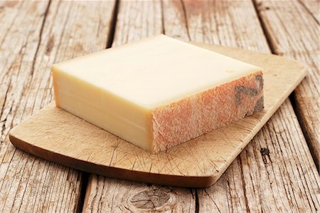 A chunk of Gruyère cheese on a chopping board Stock Photo - Premium Royalty-Free, Code: 659-07598491