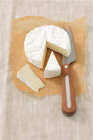 productos lácteos - Camembert on grease-proof paper, partly sliced Foto de stock - Sin royalties Premium, Código: 659-07598595