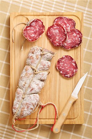 Sliced and Whole Salami on Cutting Board with Knife Foto de stock - Sin royalties Premium, Código: 659-07598695