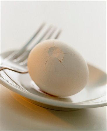 A white hen's egg with crushed shell on a plate Fotografie stock - Premium Royalty-Free, Codice: 659-07599071