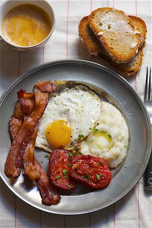Breakfast; Eggs, Bacon, Grits, Stewed Tomatoes and a Side of Toast with Coffee Foto de stock - Sin royalties Premium, Código: 659-07599194