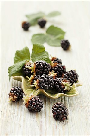 rubus - Fresh blackberries with leaves in a bowl and to one side Stockbilder - Premium RF Lizenzfrei, Bildnummer: 659-07599239