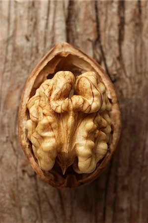 simsearch:659-07598532,k - Half a walnut against a wooden surface (close-up) Photographie de stock - Premium Libres de Droits, Code: 659-07599249