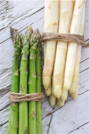 Green and white asparagus, tied in bundles, on a wooden surface Stock Photo - Premium Royalty-Free, Code: 659-07609897