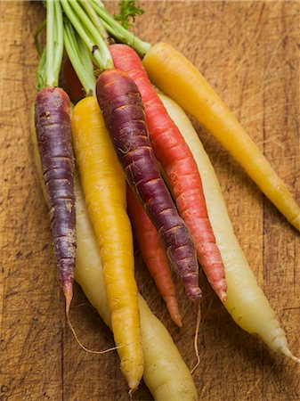 Multi-colored carrots in white, yellow, orange and red on a worn cutting board Photographie de stock - Premium Libres de Droits, Code: 659-07610010