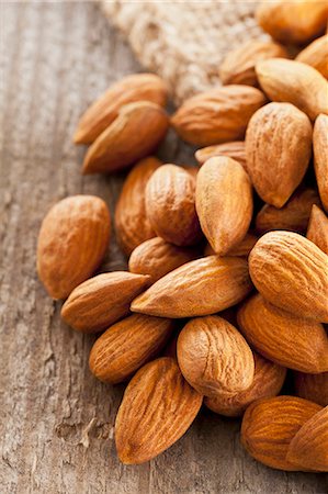 A pile of almonds on a wooden surface Fotografie stock - Premium Royalty-Free, Codice: 659-07610035