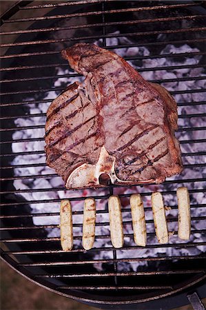 steak on grill - A T-bone steak and sausages on a barbecue Stock Photo - Premium Royalty-Free, Code: 659-07610089