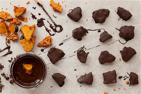 Pieces of honeycomb being dipped in dark melted chocolate Foto de stock - Sin royalties Premium, Código: 659-07610134