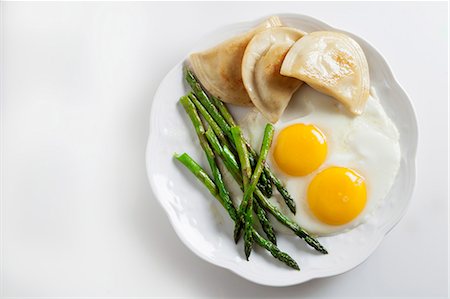 Two fried eggs with pierogi and green asparagus Photographie de stock - Premium Libres de Droits, Code: 659-07610131
