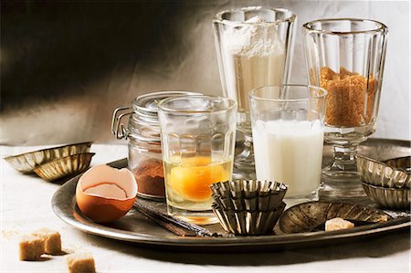 retro baking - Various baking ingredients in glasses (flour, egg, brown sugar, milk) and old-fashioned cake tins on tray Stock Photo - Premium Royalty-Free, Code: 659-07610147