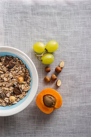 A bowl of muesli next to grapes, nuts and an apricot Photographie de stock - Premium Libres de Droits, Code: 659-07610362