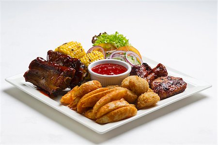 Spare ribs and chicken wings with potato wedges, corn on the cob and ketchup Stock Photo - Premium Royalty-Free, Code: 659-07610407