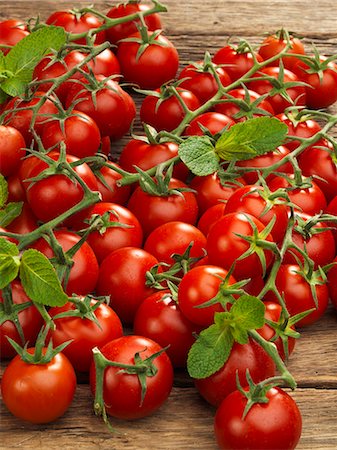 Vine tomatoes with sprigs of mint on a wooden surface Stock Photo - Premium Royalty-Free, Code: 659-07610431