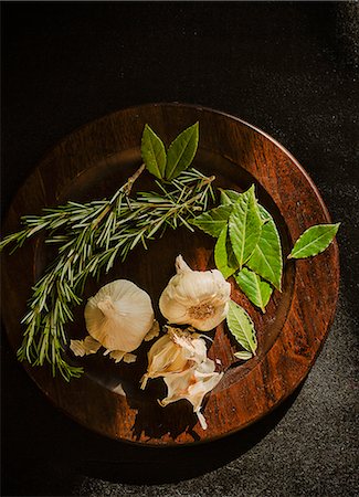 Bay leaves, rosemary and garlic on a wooden plate Stock Photo - Premium Royalty-Free, Code: 659-07738657
