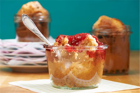 A peanut muffin with raspberry jam in a jar with a bite taken out Stock Photo - Premium Royalty-Free, Code: 659-07739399