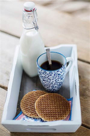 sciroppo - A cup of coffee, syrup waffles and a bottle of milk on a tray Fotografie stock - Premium Royalty-Free, Codice: 659-07739535