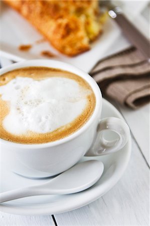 A cappuccino with milk foam and an apple turnover in the background Photographie de stock - Premium Libres de Droits, Code: 659-07739540