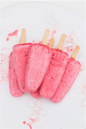 Strawberry ice cream sticks on a cake plate with bits of crushed ice Stock Photo - Premium Royalty-Free, Code: 659-07958411