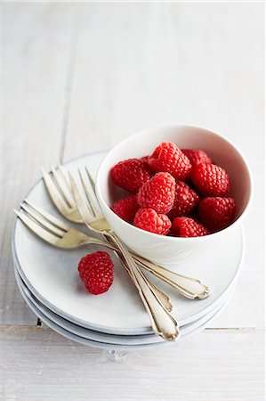 simsearch:659-03537384,k - A bowl of raspberries on a stack of plates with cake forks Foto de stock - Royalty Free Premium, Número: 659-07958953