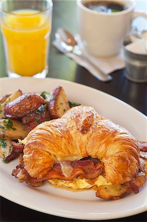 potatoes eggs bacon - A croissant with scrambled eggs, bacon and cheese served with a side of sauteed potatoes, orange juice and coffee Stock Photo - Premium Royalty-Free, Code: 659-07959184