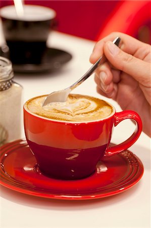 simsearch:659-06153925,k - A hand stirring a hot cappuccino decorated with a heart Stock Photo - Premium Royalty-Free, Code: 659-07959484