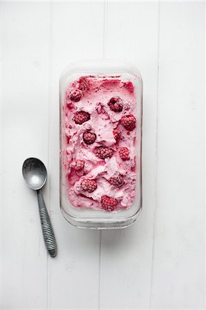 A tub of frozen raspberry yogurt next to an ice cream scoop Stock Photo - Premium Royalty-Free, Code: 659-07959510