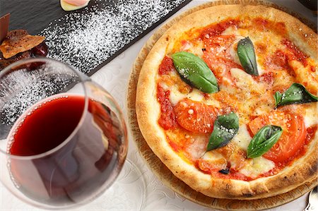 Pizza Napoli with tomatoes, cheese and basil served with a glass of red wine Foto de stock - Sin royalties Premium, Código: 659-07959564