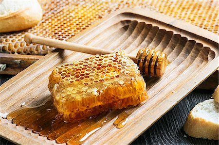 Honeycomb with a honey spoon in an old wooden bowl Photographie de stock - Premium Libres de Droits, Code: 659-07959744