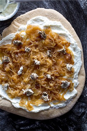 A pizza with cream cheese, caramelised onions and goat's cheese, unbaked Stock Photo - Premium Royalty-Free, Code: 659-07959945