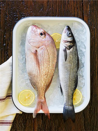 fish overhead - A red snapper and a sea bass on ice cubes with lemon slices in an enamel pan Stock Photo - Premium Royalty-Free, Code: 659-08147059
