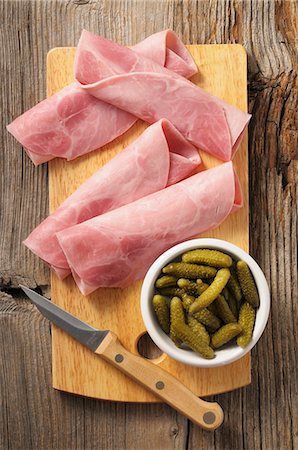 Rolled ham and gherkins on a chopping board Stock Photo - Premium Royalty-Free, Code: 659-08147079