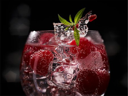 An exotic raspberry drink with whole raspberries, ice cubes and sugar decoration with pomegranate seeds Stock Photo - Premium Royalty-Free, Code: 659-08147099