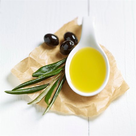 A spoonful of olive oil, olive leaves and black olives on a piece of paper Stock Photo - Premium Royalty-Free, Code: 659-08147185